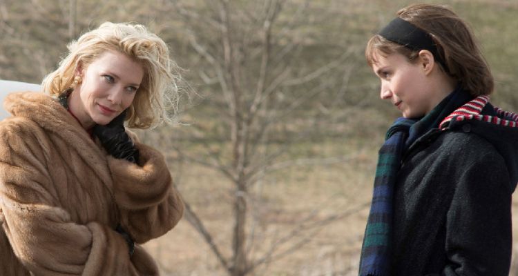 Image still from Carol of two women looking at each other teasingly in an outdoor setting.