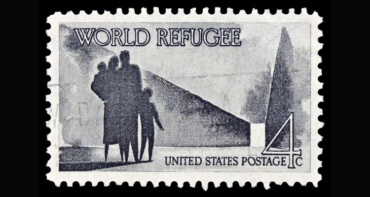 A U.S. postal stamp with four silhouetted figures - two adults and two children - looking down a corridor to an opening that it well-lit; the stamp's text reads "World Refugee" and "United States Postage 4 cents"