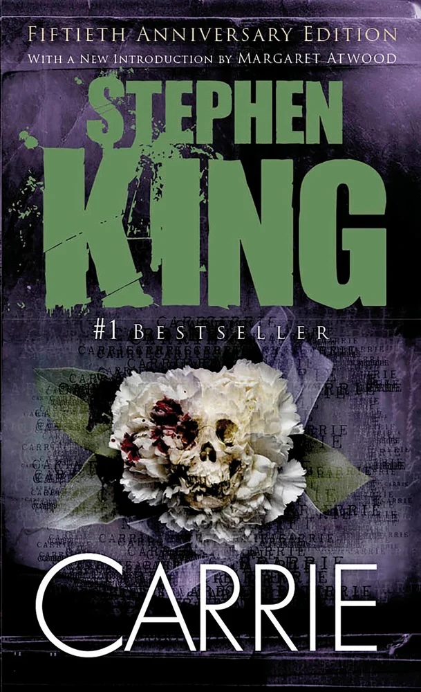 Carrie by Stephen King book cover, depicting a skull on a white flower, the author's name in a bold green font at the top, and the title in a thin white font at the bottom. It is on a purple and black background.