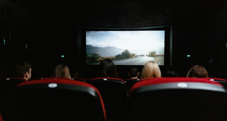 Image depicting movie theater from the perspective of a movie viewer. The screen features a road.