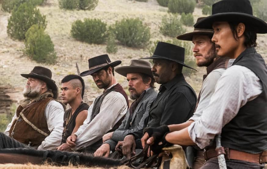 A still from The Magnificent Seven (2016). Seven cowboys sit on their horses and stare off into the distance. Three of the men are White. The remaining four are Indigenous, Mexican, Black, and Chinese.