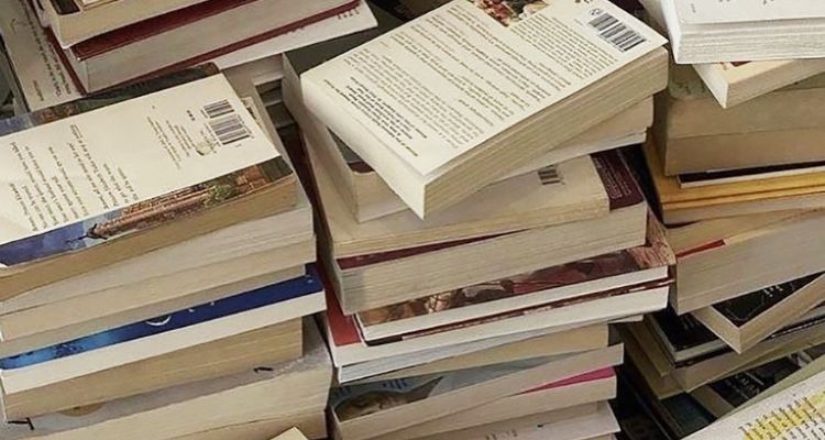There are wo full and three partial book piles visible. Of the two full books we can see, their back covers are facing up.