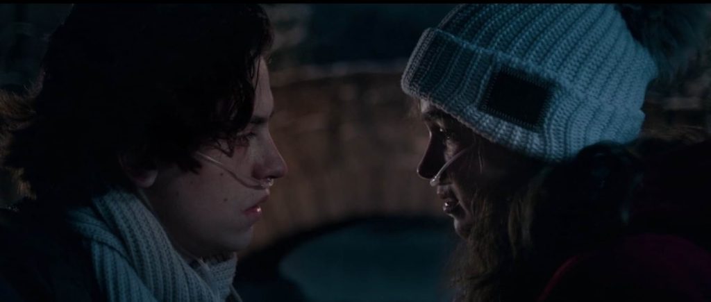 A still from Five Feet Apart. Two teens wearing oxygen tubes stand close as if they are about to kiss.