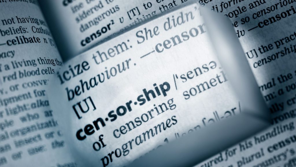 A dictionary open to the definition of "censorship," which has been magnified.