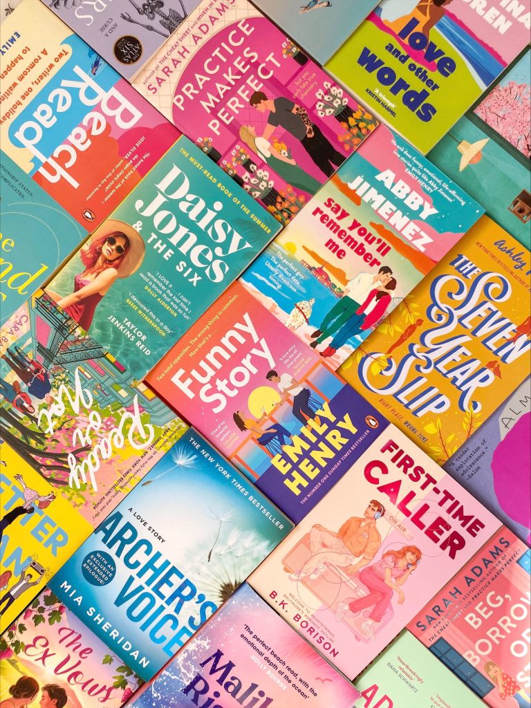 Colorful book covers arranged to perfectly line up in differing orientations. Visible book titles and authors include Daisy Jones & The Six by Taylor Jenkins Reid, Say You'll Remember Me by Abby Jimenez, Funny Story by Emily Henry.
