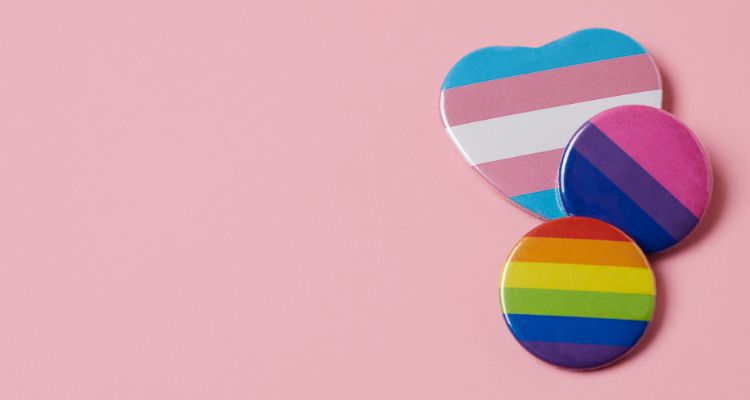 A pink background with the trans, bisexual, and pride flag badges on it.