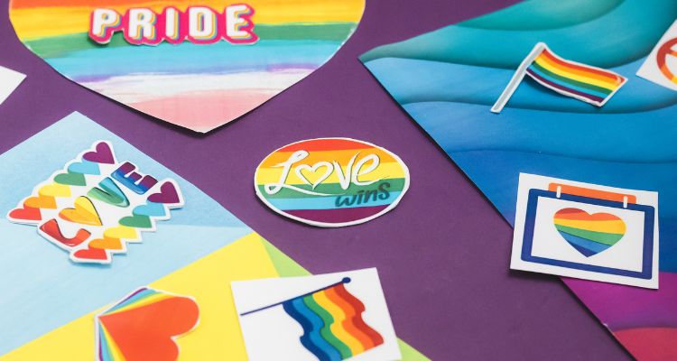A purple table cloth overed with different Pride stickers and crafts.