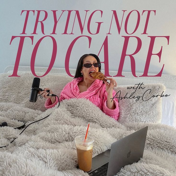 Trying Not To Care podcast cover. Ashley Corbo in bed eating a croissant with her microphone and laptop.
