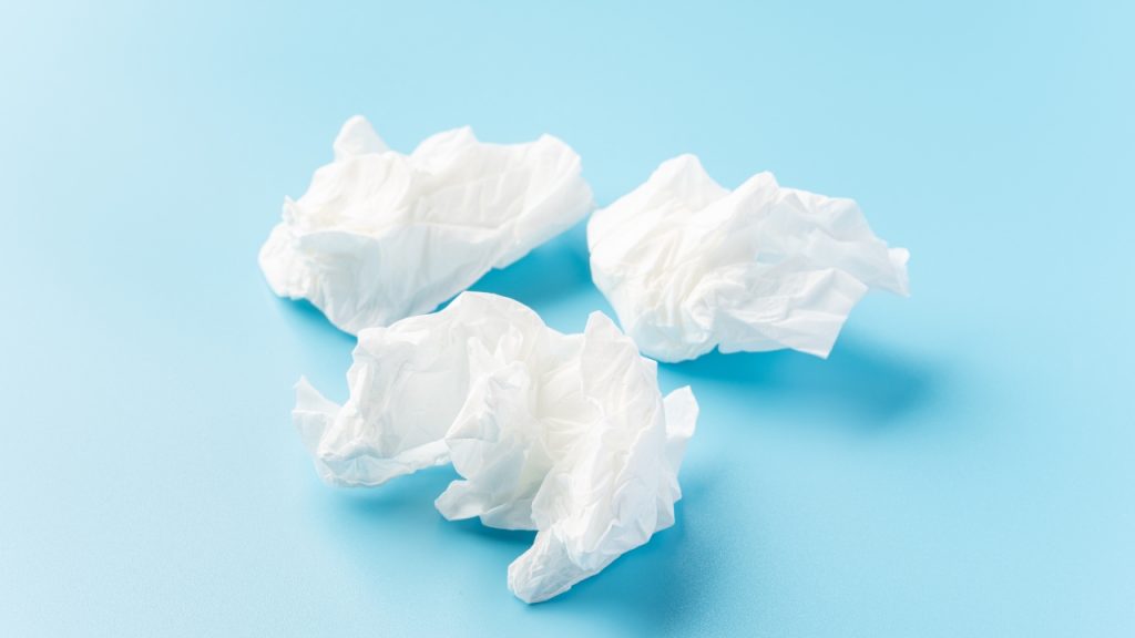 A light blue background with three crumpled white tissues.