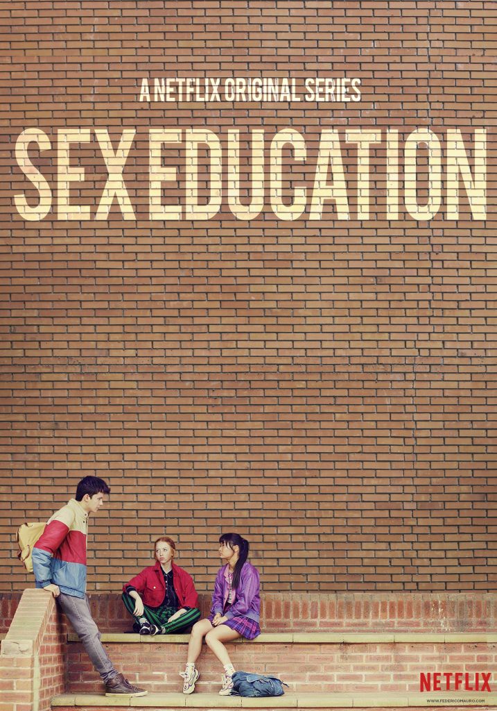 Sex Education poster by Netflix depicting three teenagers sat on and in front of a brick wall, on which the title has been painted. Leaning against a wall is a black haired boy in profule, wearing a yellow backpack, beige, red, and blue striped jacket, jeans and trainers. Sat cross-legged on the wall is a ginger girl in red jacket and green and black striped trousers. The girl next to her has black bangs and her long hair up in a ponytail. She is wearing a purple jacket, a pink and blue plaid skirt, and trainers. A blue bag lies next to her feet.