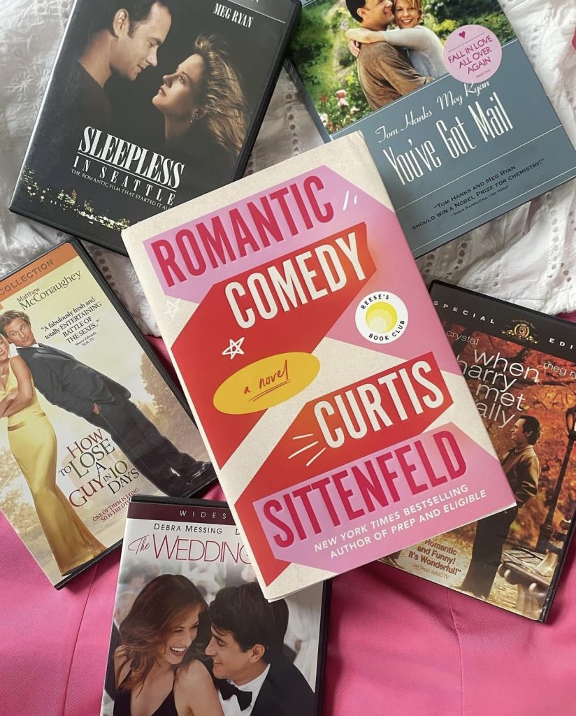 The pink and blue romance book cover Romantic Comedy by Curtis Sittenfeld on top of DVDs of romantic comedy films: Sleepless in Seattle, How To Lose A Guy in 10 Days, When harry met Sally, and You've Got Mail.