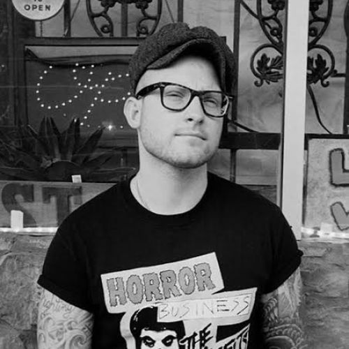 Black and white image of Rob Rufus wearing a hat, glasses, and graphic t-shirt.
