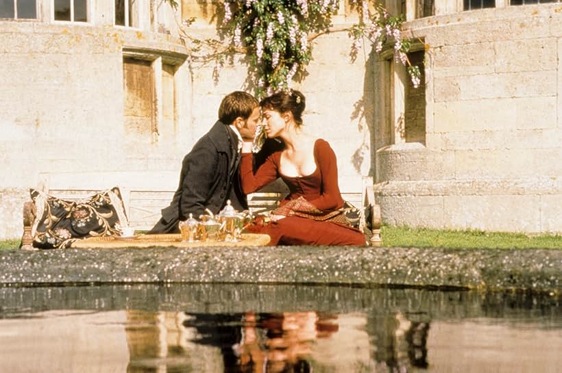 Image from Mansfield Park (1999) of a woman and a man sitting together with their faces very close together. They are sitting outside.