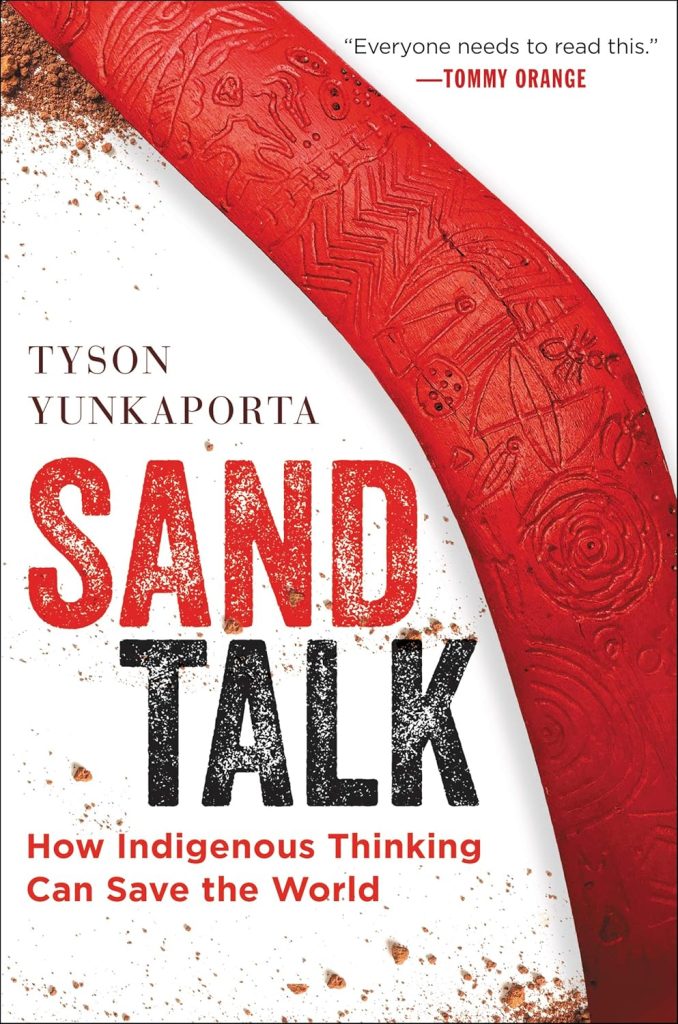Sand Talk by Tyson Yunkaporta book cover. A piece of wood painted red with carvings on it.