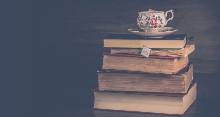 Image depicting a stack of old books with a cup of tea on top.