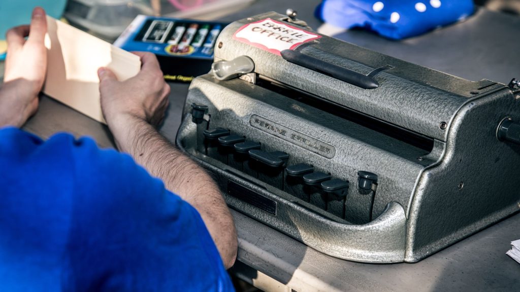A braille embosser sitting on a table being loaded by a person sitting in front.