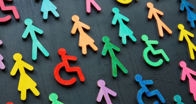 Black background with rainbow popsicle sticks shaped like men, women, and people in wheel chairs spread evenly across the page. Representing inclusion.