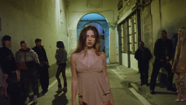 Image of Addison Rae from the Aquamarine music video in an alley wearing a beige top.