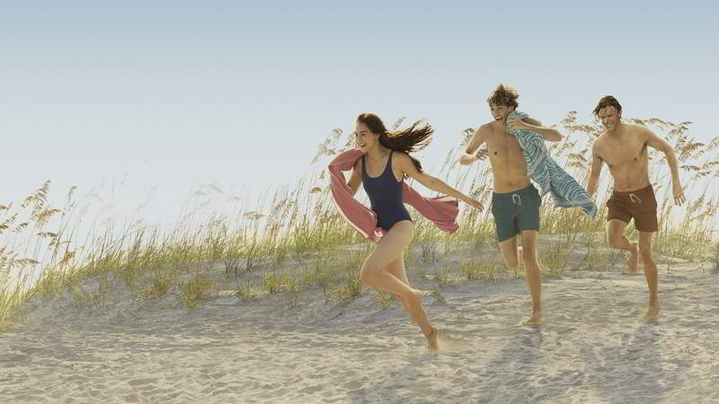 Belly runs in front of Jeremiah and Conrad on the beach