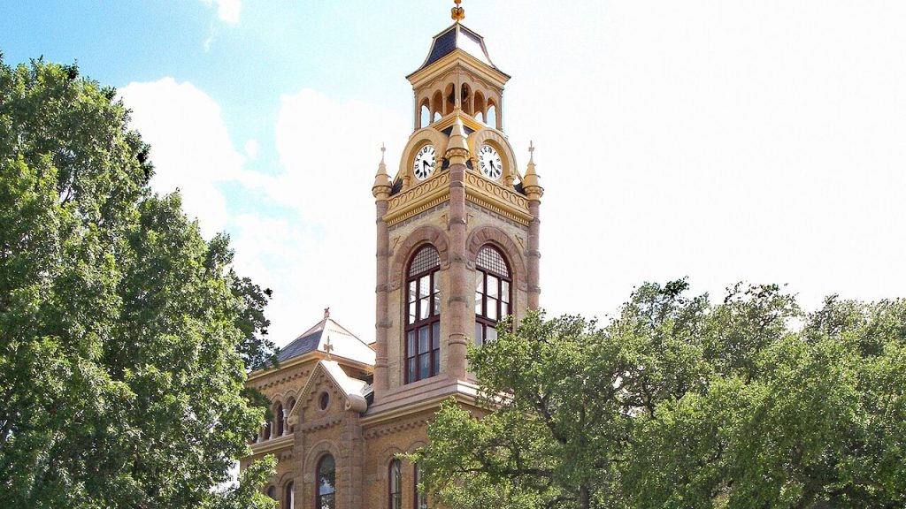 A picture of Llano County Courthouse, surrounded by green trees.