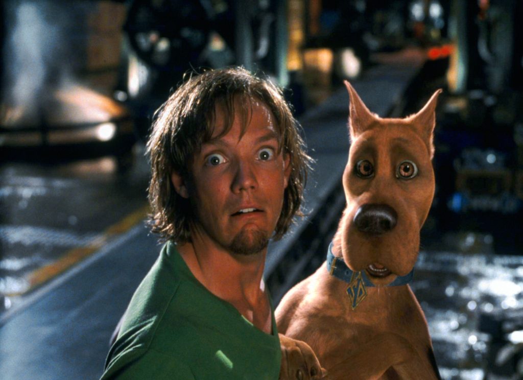 Still from Scooby-Doo (2002), depicting a close-up of Shaggy and Scooby-Doo with shocked expressions. The background is blurry and dark.