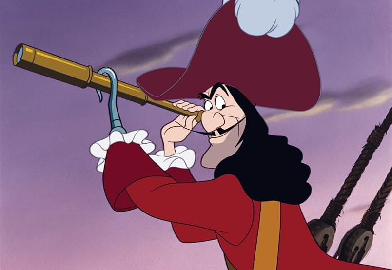 A still from the 1953 movie Peter Pan. An animated man with long black hair and a pointed mustache wears a large red hat and matching coat with frilled sleeves. He holds out a gold spyglass against a purple sky and has a silver hook in place of his left hand.