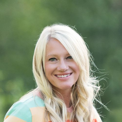 Romance author Kortney Keisel, a light skinned blond woman, smiles at the camera while being outside.