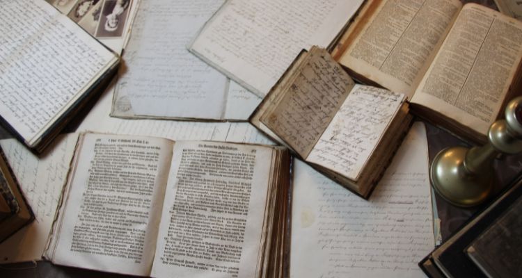 Depicts various old books opened up covering the floor.