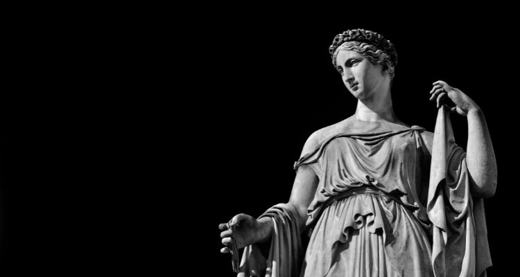 Depicts a statue of a woman from greek mythology against a black background.