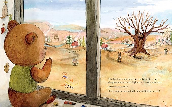 Page spread from The Wishing Tree by Kallie George, depicting a brown bear in a green vest looking outside a window. Outside the window is a distant mountainous landscape, some small houses, and a big brown tree with only one leaf on it.