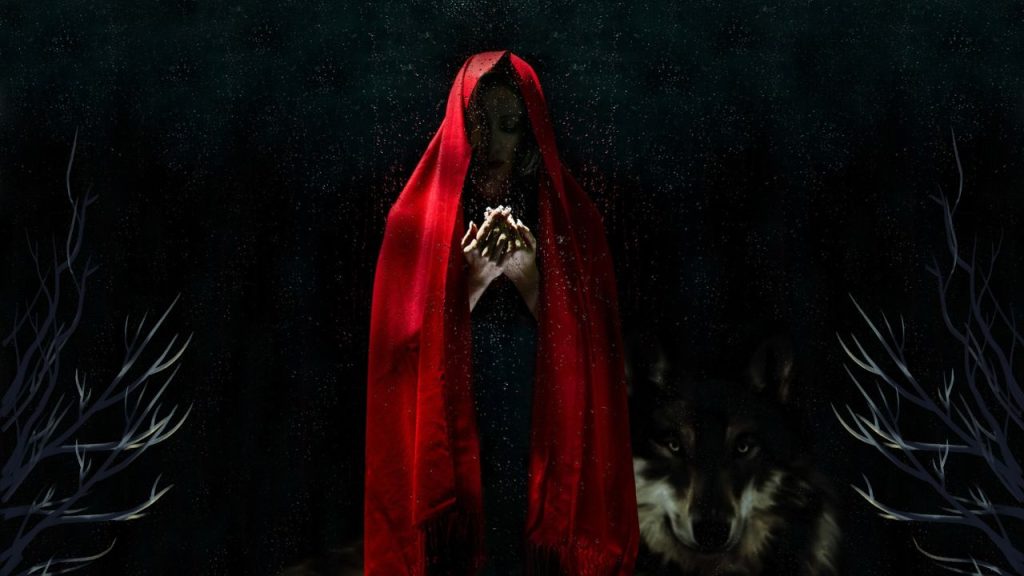 A hyper-saturated photo of a woman in the center of a dark woods backgrounded wearing a vibrant red hood cape.