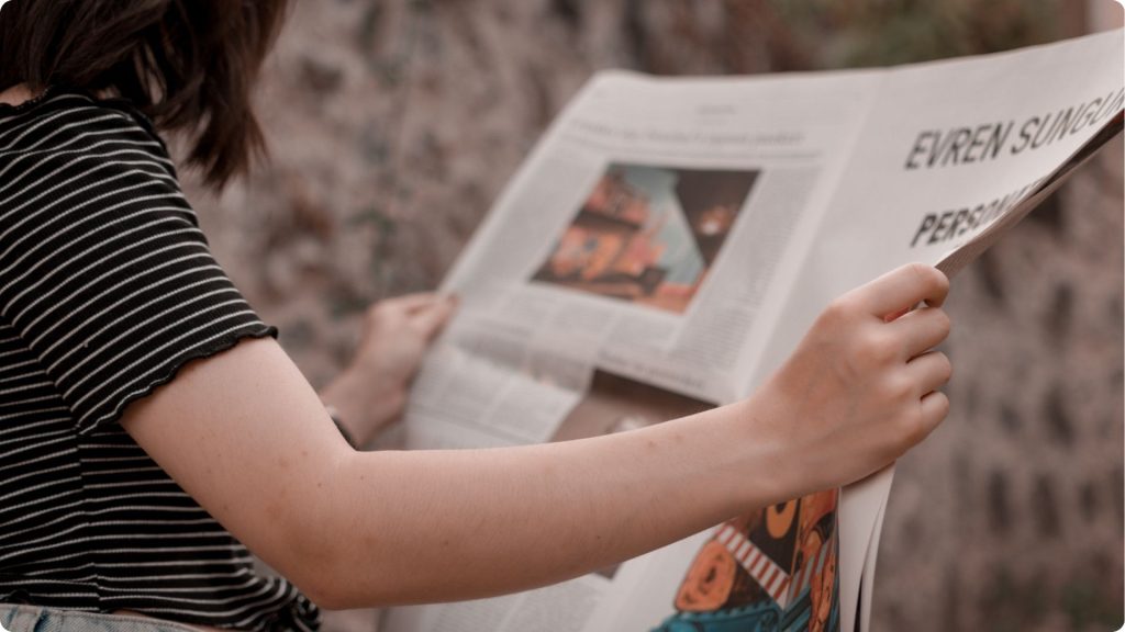 A close-up of a middle school aged child reading a newspaper.