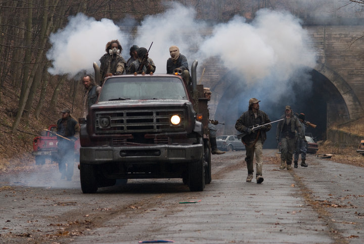 A still from the film adaptation of The Road, showing cannibals riding in the back of a truck.
