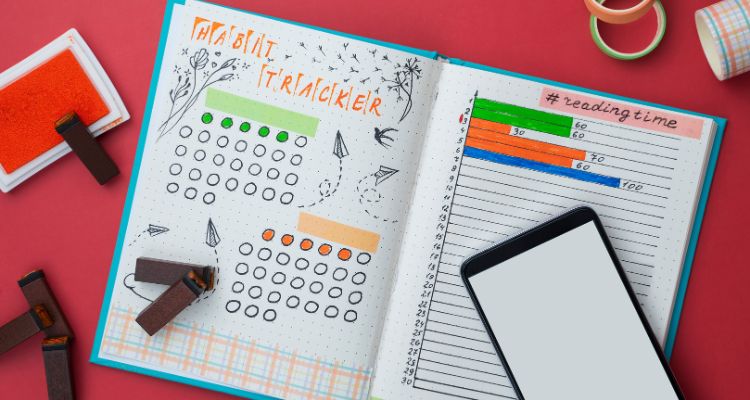 Depicts open bullet journal with a habit tracker and a reading time tracker filled out in colorful markers.