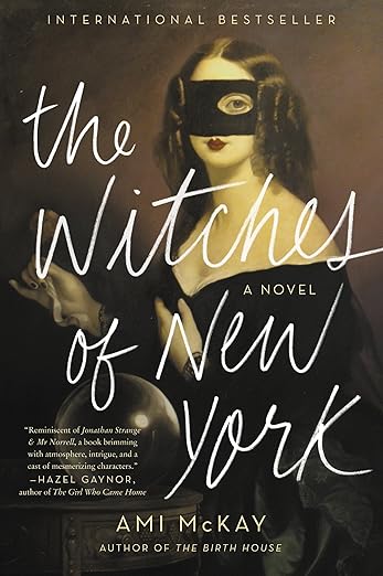 The Witches of New York by Ami McKay book cover, a painting of a woman with a black dress and mask on her face that makes her lips, jaw, and right eye visible. The background is brown, and the title is written across the book in white, handwritten letters.