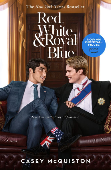 Book cover of "Red, White & Royal Blue" by Casey McQuiston. Two men sit on a luxurious red sofa, dressed in a suit and royal attire. They share a friendly gaze.