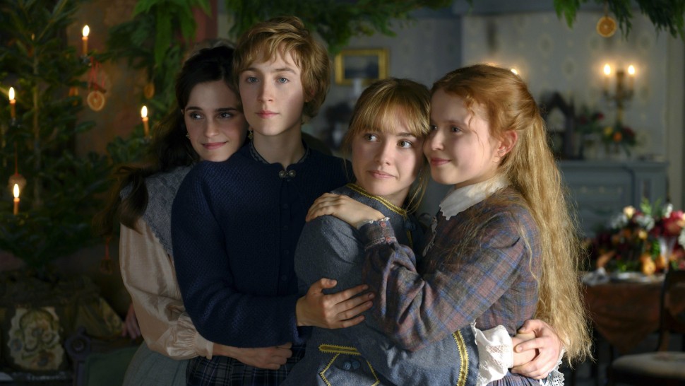 Movie still from Greta Gerwig's 2019 adaptation of 'Little Women'. Image depicting four young women stood hugging one another and smiling. Christmas decorations and garlands adorn the room behind them.