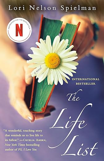 The Life List by Lori Nelson Spielman book cover, depicting someone holding a book which has a daisy between the pages. The background is out of focus, but depicts the purple clothing of the person holding the book. The title is written in elegant white text at the bottom right of the book.