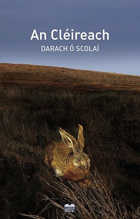 An Cléireach ("The Clerk") by Darach Ó Scolaí. A photograph of a lifelike brown hare sitting alert under a darkening sky, with the title centered above in white.
