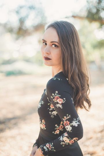 Autumn Krause wearing a black and floral print dress, standing outside.
