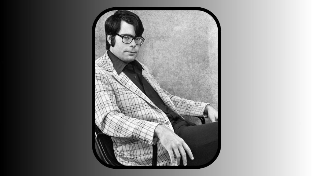 On a background fading from black to silver, there is a portrait of Stephen King from the late 1970s or '80s. He's wearing black clothes under a lighter suit jacket, as he leans back in a computer chair.