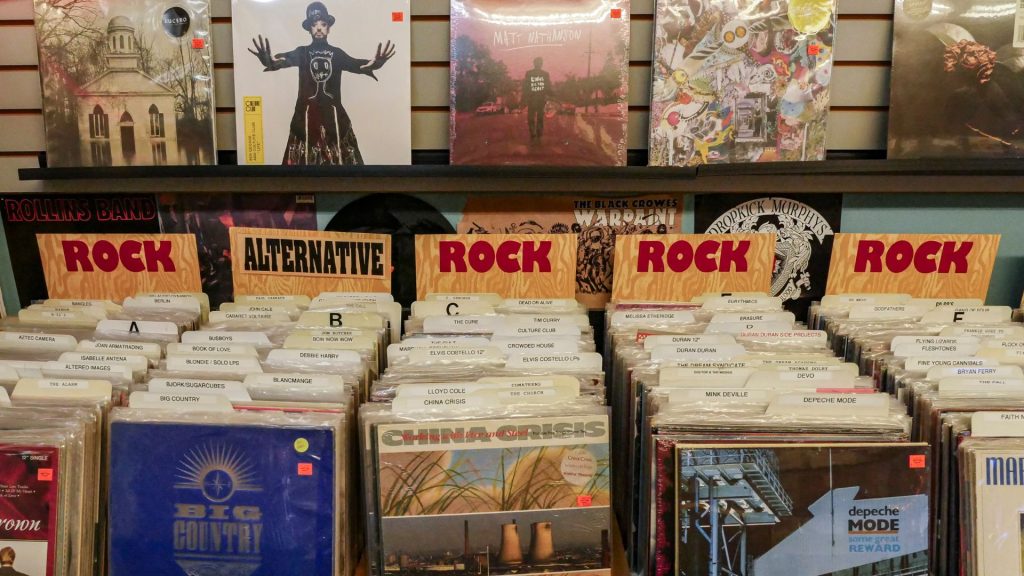 A row of rock and alternative records displayed on a shelf in a record store arranged in alphabetical order.