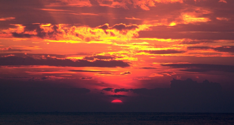 A red-tinted sunset sky over a large body of water.