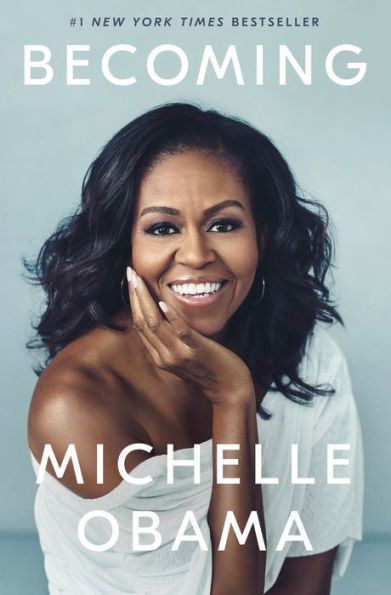 Book cover of "Becoming" by Michelle Obama. Features a smiling Michelle Obama, wearing a white off-shoulder top against a light blue background.