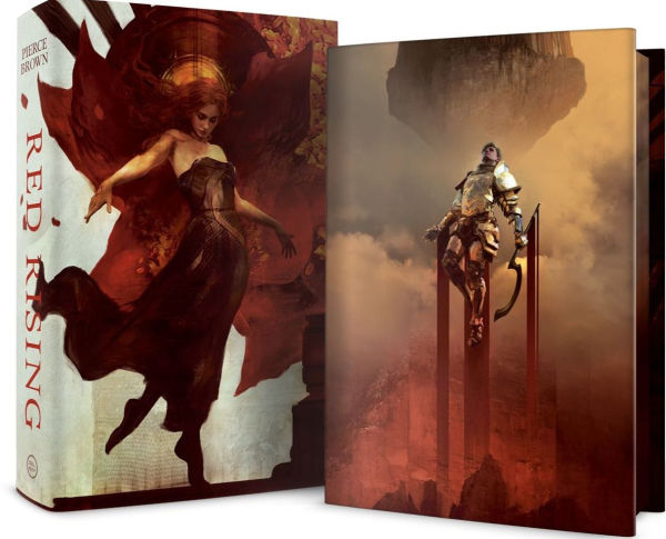 Deluxe slipcase edition of “Red Rising” by Pierce Brown. The slipcase shows an illustration of a woman in a flowing black dress against fiery red tones, while the book itself features a gold-armored warrior standing on towering pillars above a smoky battlefield.