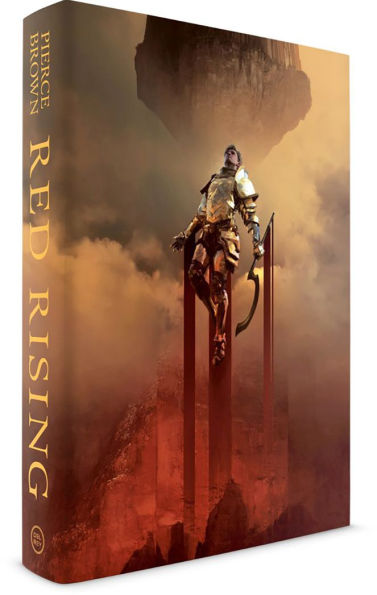 Deluxe hardcover of “Red Rising” showing a gold-armored warrior standing on tall red pillars rising out of smoke, holding a large curved weapon.