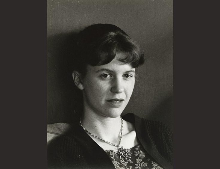 Black and white portrait of the poet Sylvia Plath looking away distantly with her hair tied up.