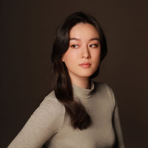 Author Chloe Gong, wearing a grey semi turtle neck top, looking to the side.