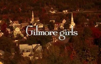 A still from the opening credits of Gilmore Girls. The title is centered on the screen in white text with a drop shadow over a warm-filtered image of a Connecticut town during the fall.