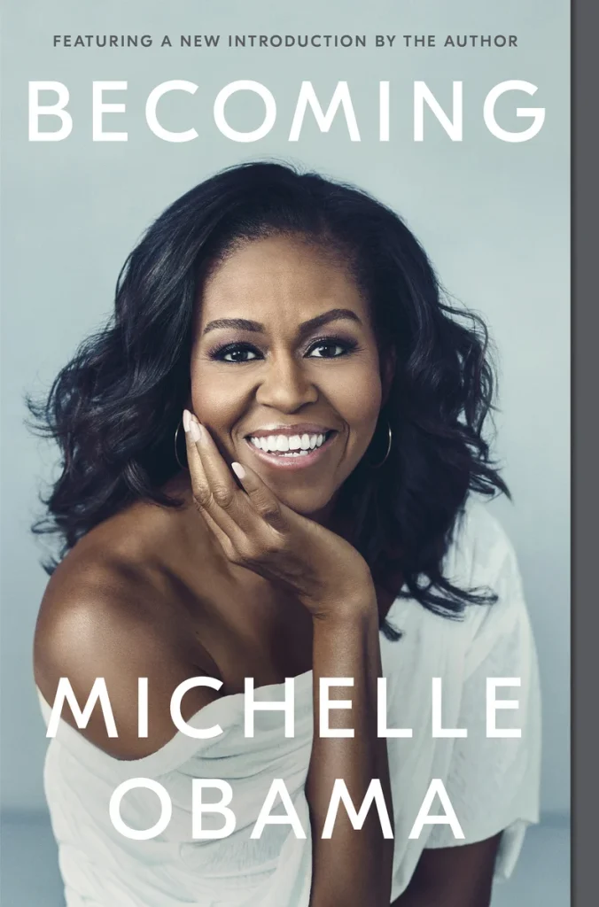 Becoming, a memoir by Michelle Obama book cover depicts Michelle Obama smiling with her hand on her hand on her face.